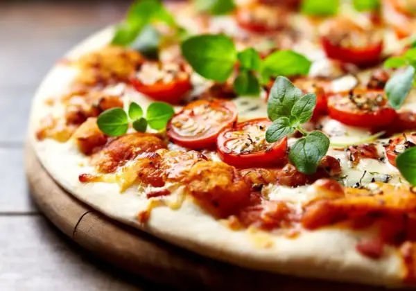 Pyszna pizza bez drożdży z pomidorkami koktajlowymi i świeżą bazylią, idealna na szybki obiad.