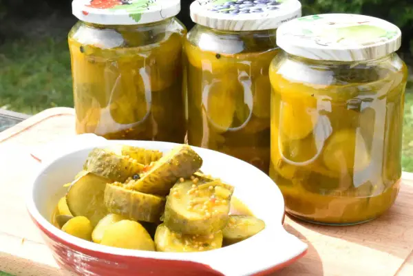 Słoiki z ogórkami z curry i miseczka z pokrojonymi ogórkami. Idealne na letnie przetwory.
